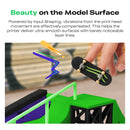 3D printed skateboard model with hand holding it, set against a blurred indoor background.