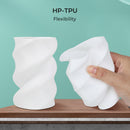 White HP-TPU material being stretched by a hand on a wooden surface with a green background
