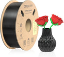 A spool of Creality Hyper Series 3D printer filament next to a black textured vase holding two red knitted roses, on a white background.