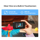 A hand holds a small black built-in touchscreen camera or monitor in front of a colorful parrot toy. Text at the top reads 'Clear View on a Built-In Touchscreen' with icons for '3-inch HD Touchscreen' and '500 nit Peak Brightness'.
