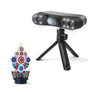 A black portable projector on a small tripod stand, shown alongside a colorful 3D-printed display model that demonstrates its projection capability, against a clean white background.