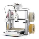A 3D printer with a white and silver frame, shown with filament spools on both sides. The image is set against a solid black background with a white surface at the bottom, and a small text overlay at the bottom reads '* Filaments sold separately.